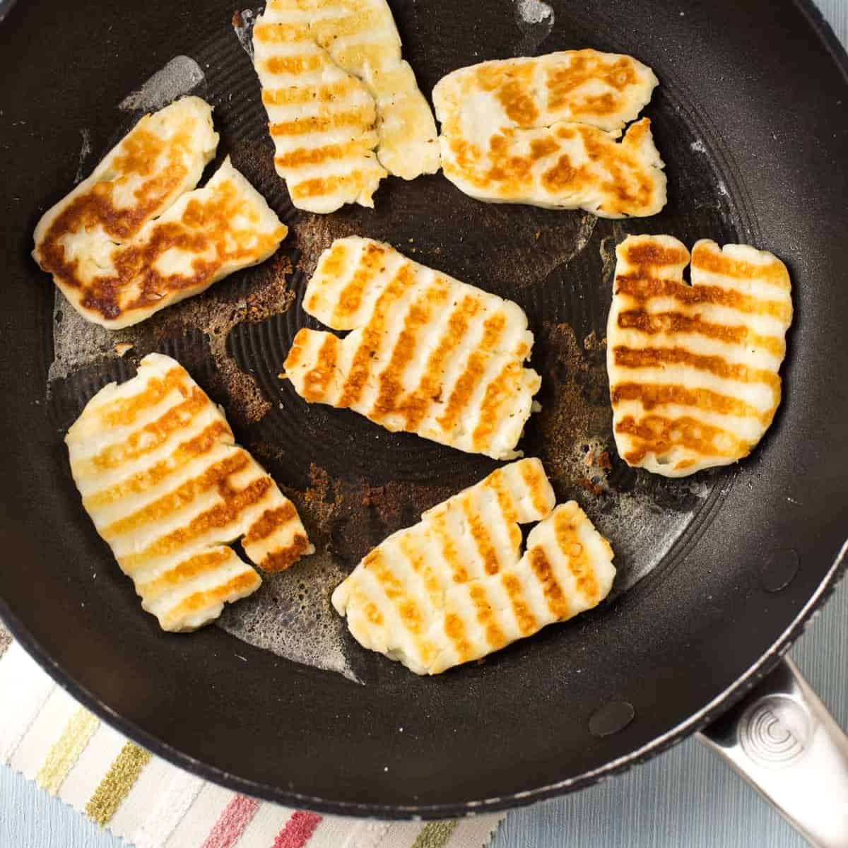 Crispy fried halloumi in a frying pan.