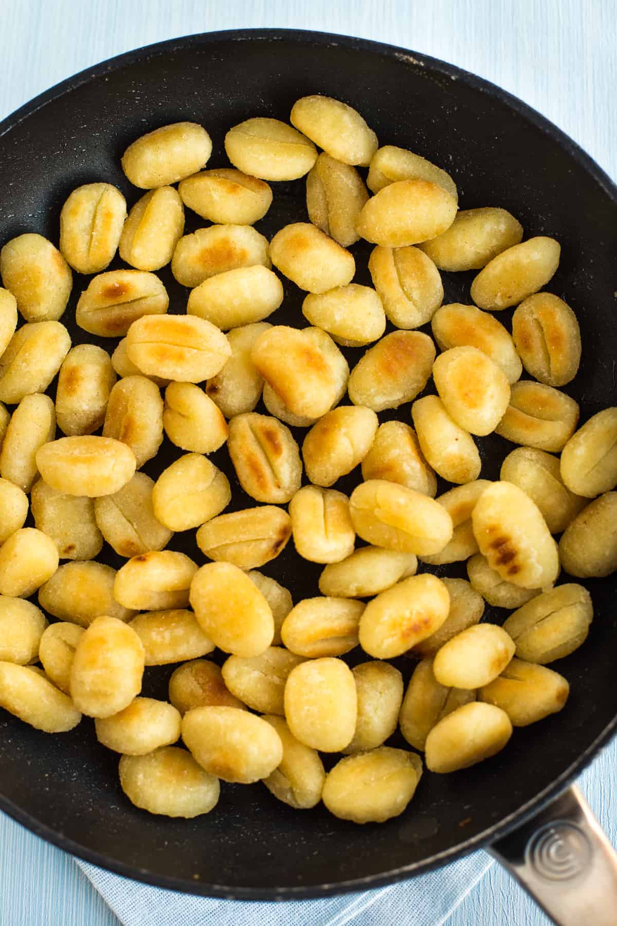 Crispy fried gnocchi in a frying pan.