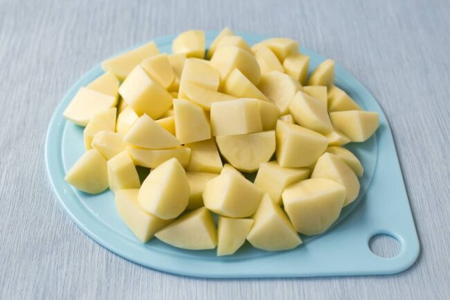 Peeled and chopped raw potatoes on a board.