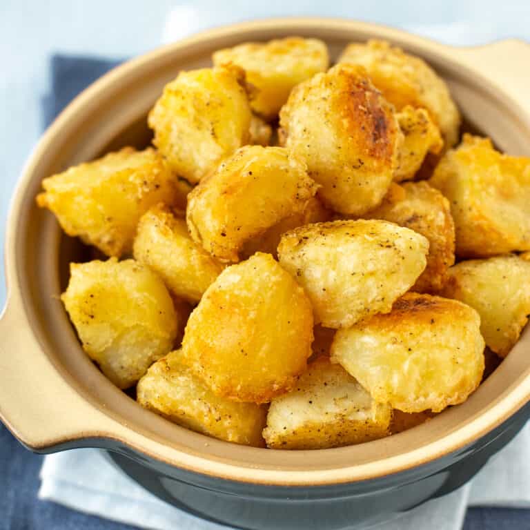 A serving bowl full of crispy roast potatoes.