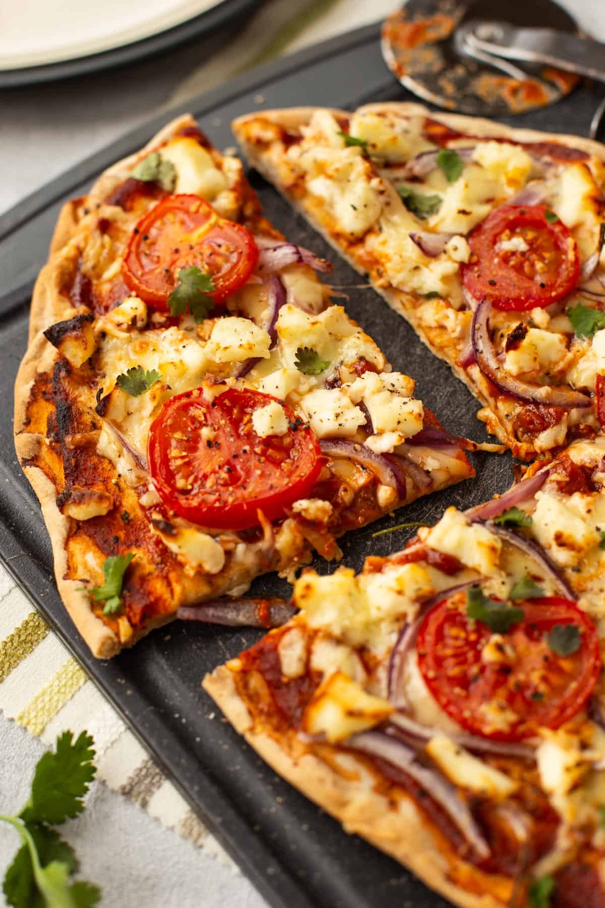 A slice cut from a naan bread pizza with paneer.