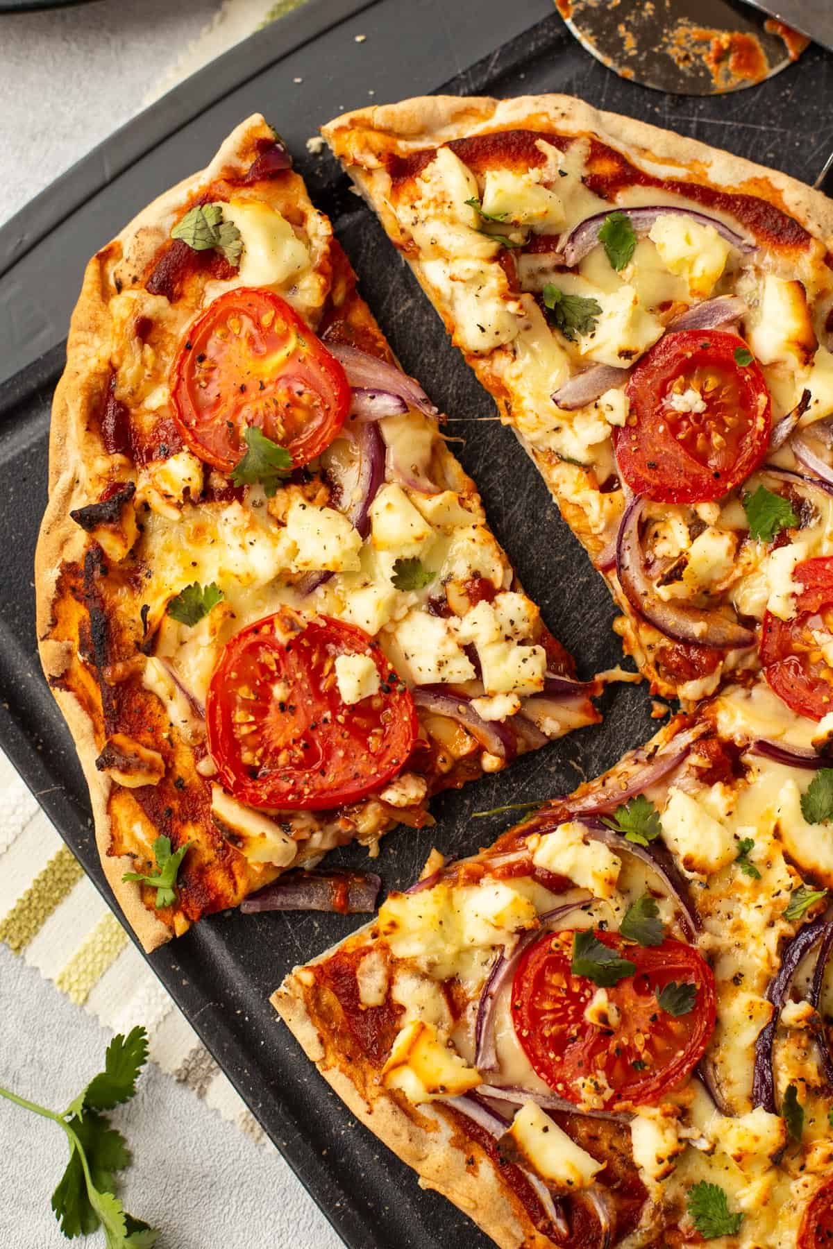 A slice cut from an Indian naan bread pizza with paneer.