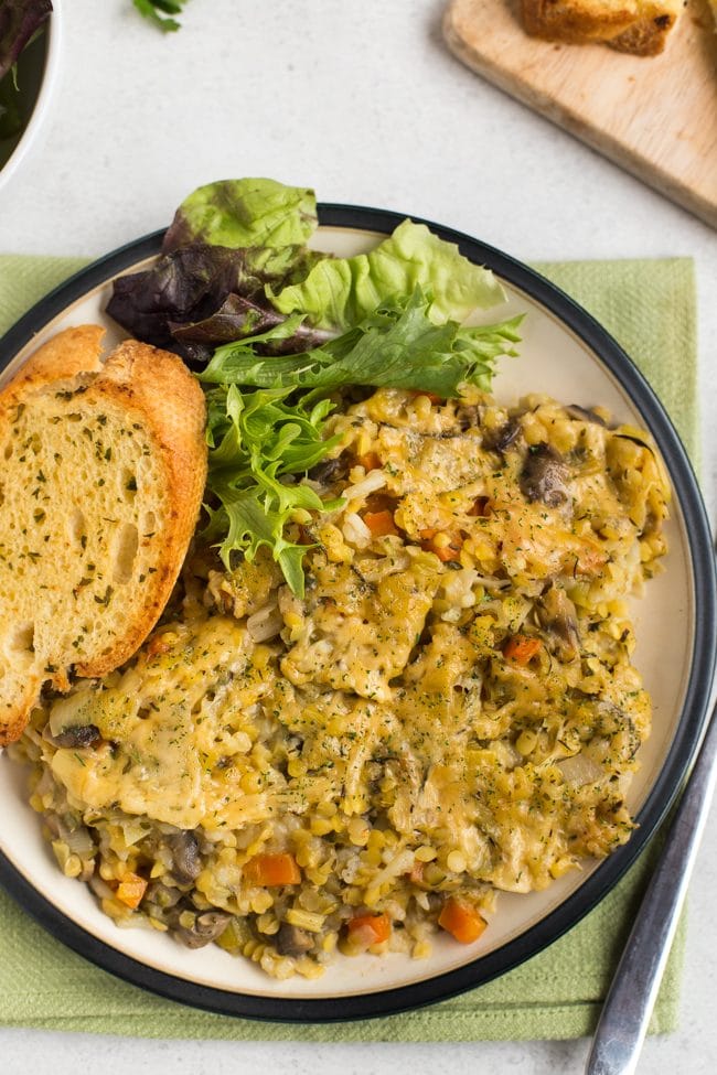 Portion of Instant Pot very veggie lentil bake on a plate with garlic bread and salad
