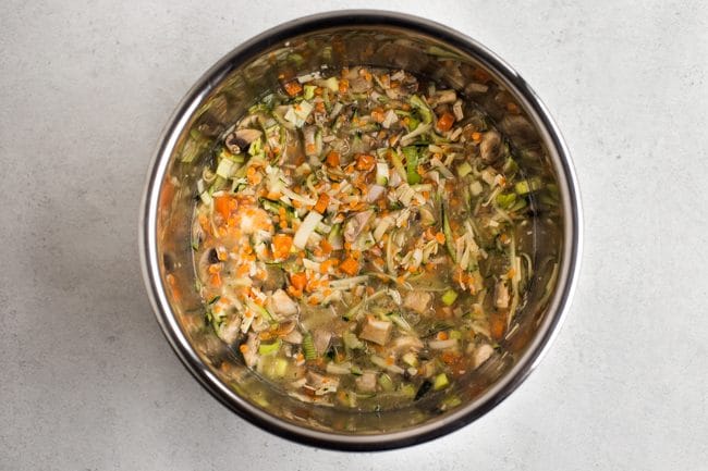 Uncooked lentils, rice and vegetables in vegetable stock in the Instant Pot bowl