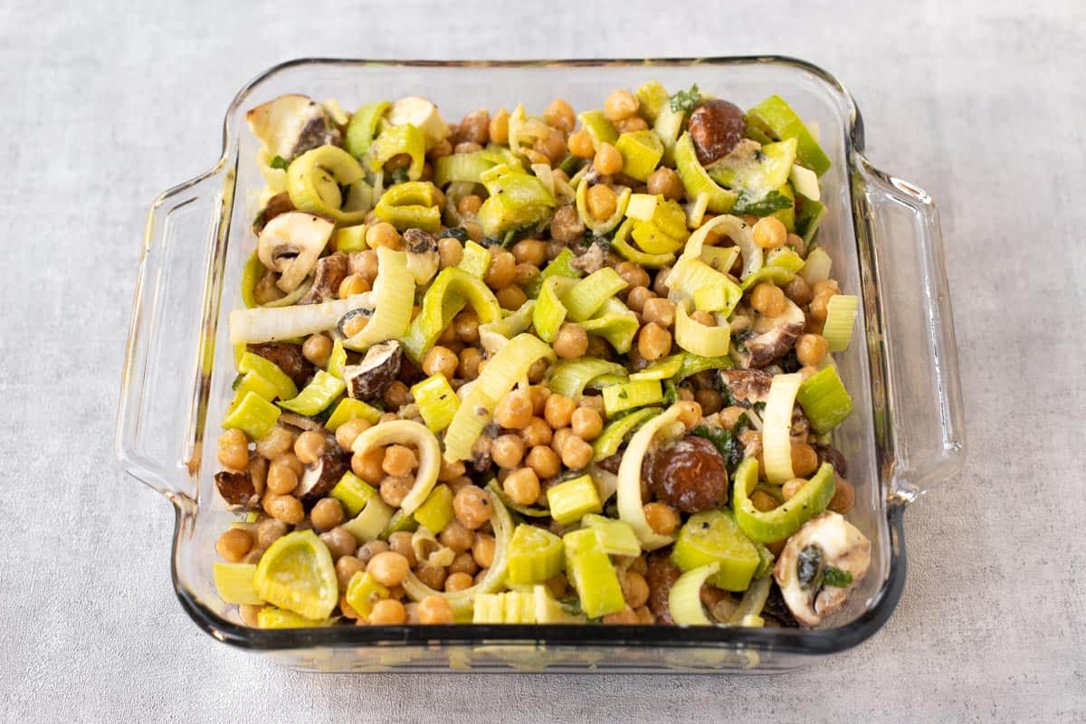 Uncooked chickpea casserole with leeks in a baking dish.