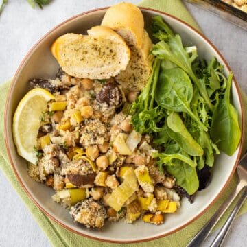 Portion of chickpea casserole in a bowl with garlic bread and salad.