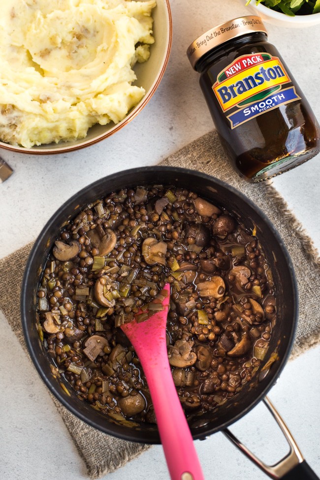 Lentil and mushroom stew in a saucepan with a jar of Branston pickle