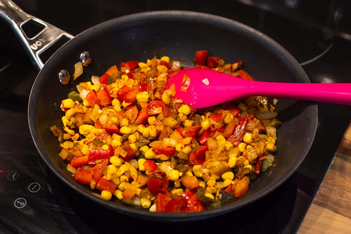 Spiced vegetables cooking in a frying pan.