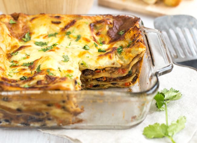 Mexican vegetarian lasagne in a baking dish with a slice removed