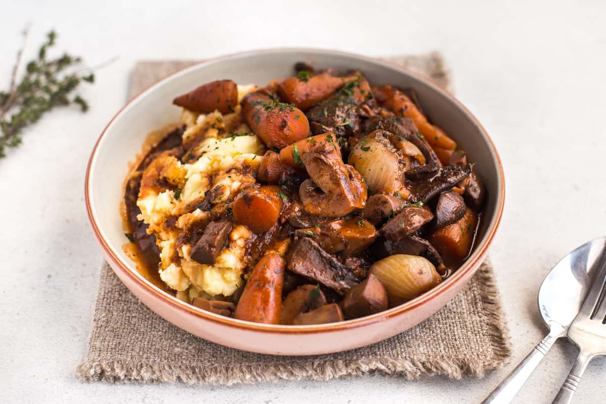 Portion of mushroom bourguignon and mashed potato in a bowl.