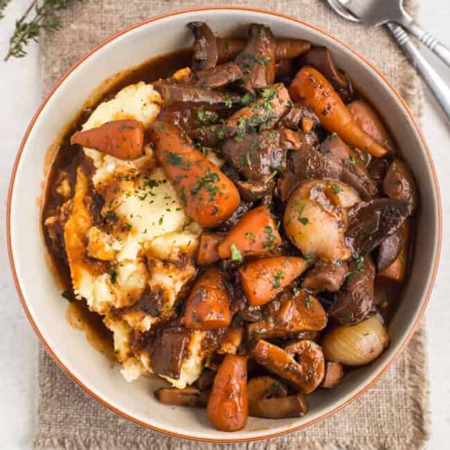 A bowlful of rich mushroom bourguignon stew served over mashed potato.