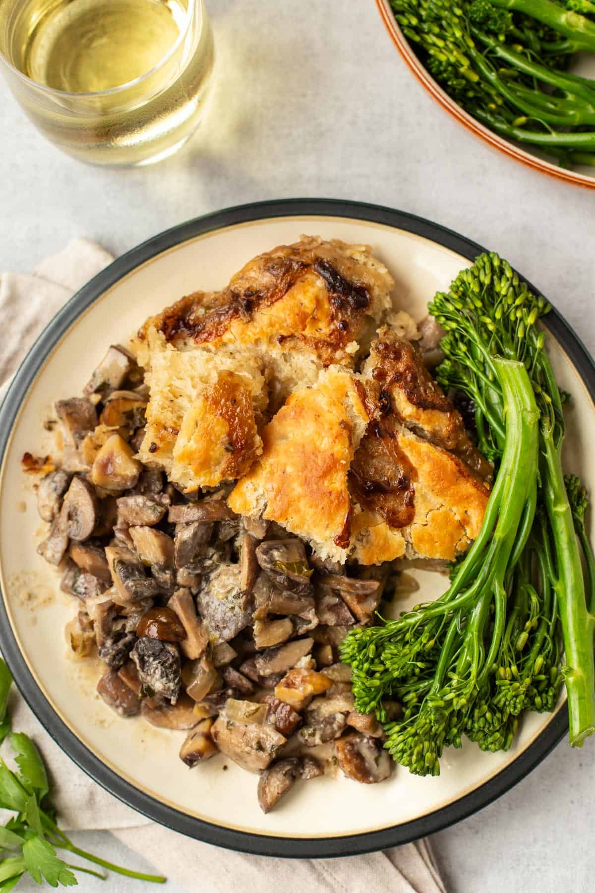 A portion of mushroom pie on a plate with a suet crust and some broccoli.