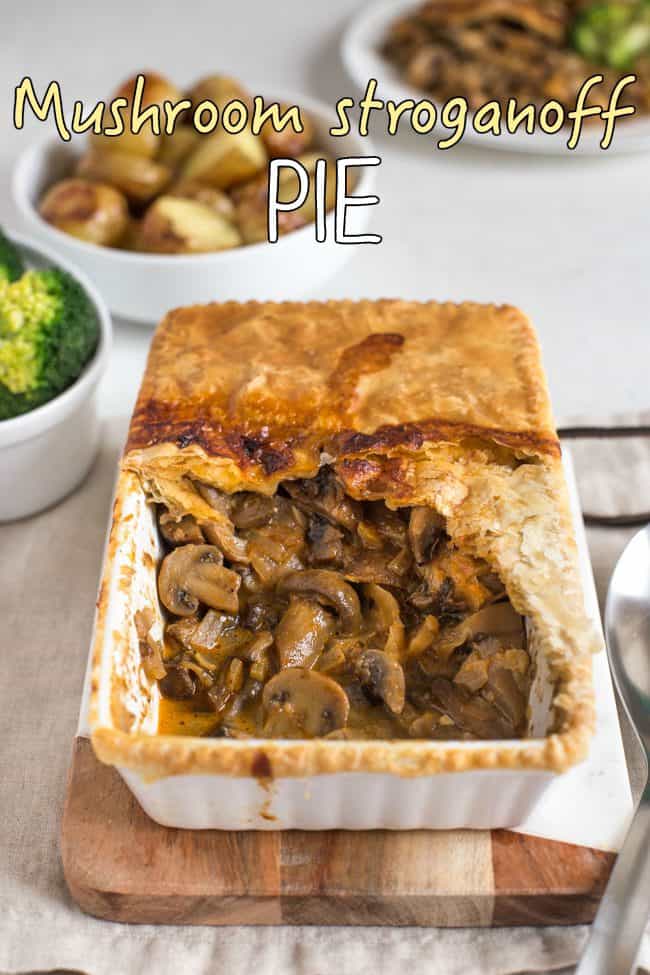 Mushroom stroganoff pie served on a wooden board, with a scoop removed