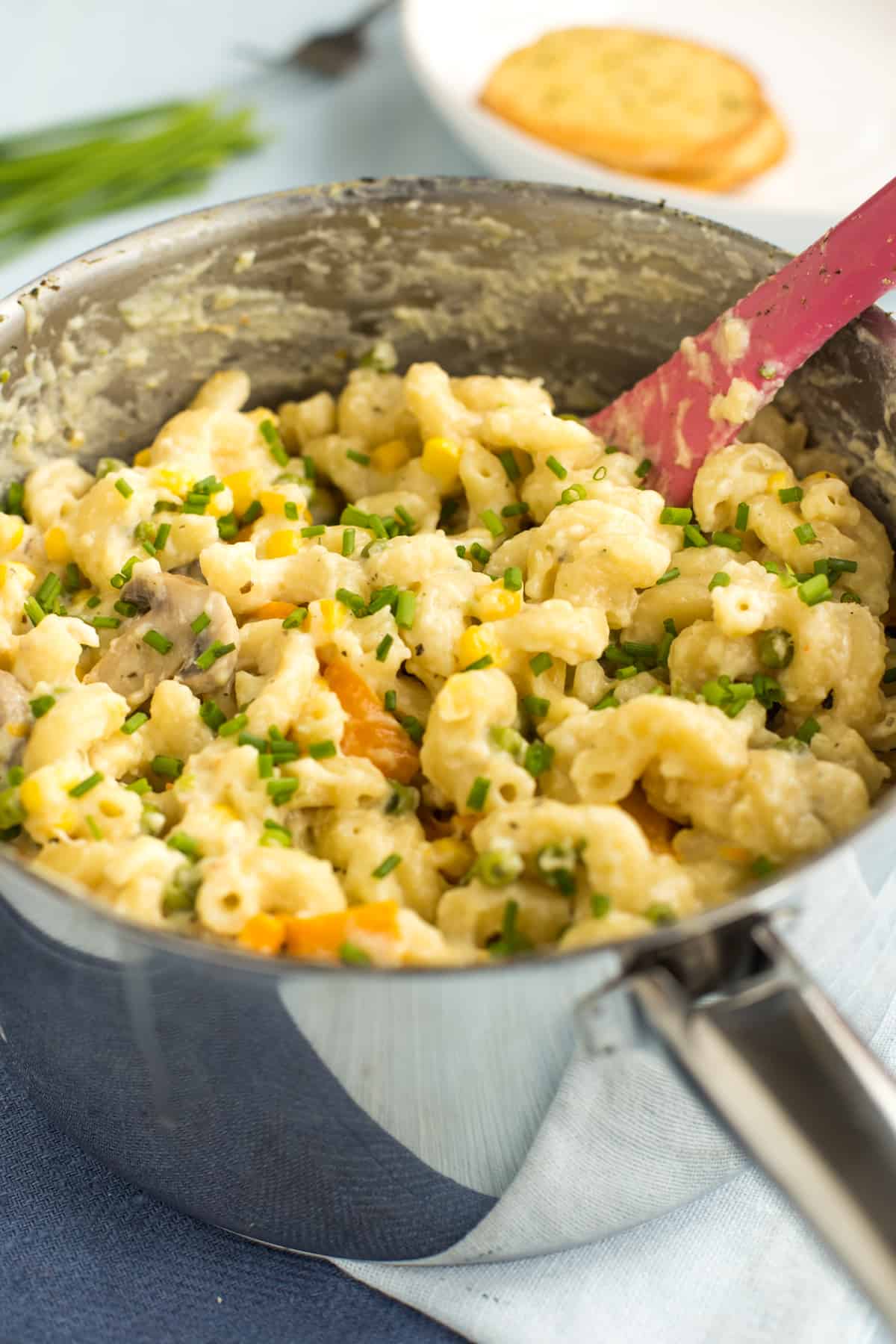 One pot creamy veggie pasta in a saucepan topped with chives.