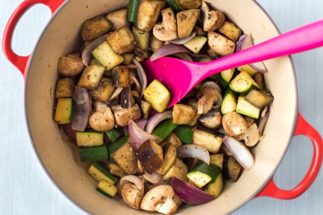 Vegetables cooking in a Le Creuset casserole dish.