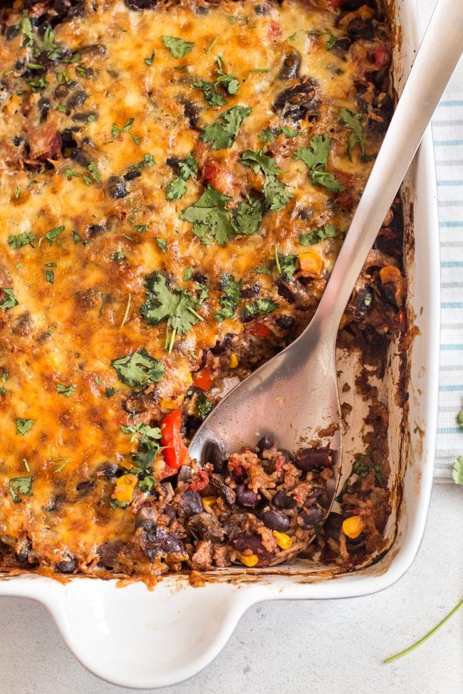 Cheesy vegetarian chilli and rice bake shot from above, with a spoon taking a scoop
