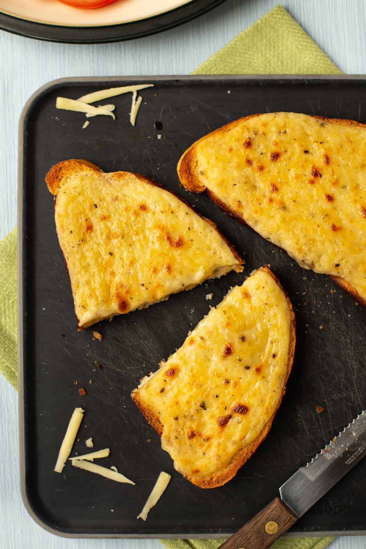 Aerial shot of a slice of cheesy Welsh rarebit on a cutting board.