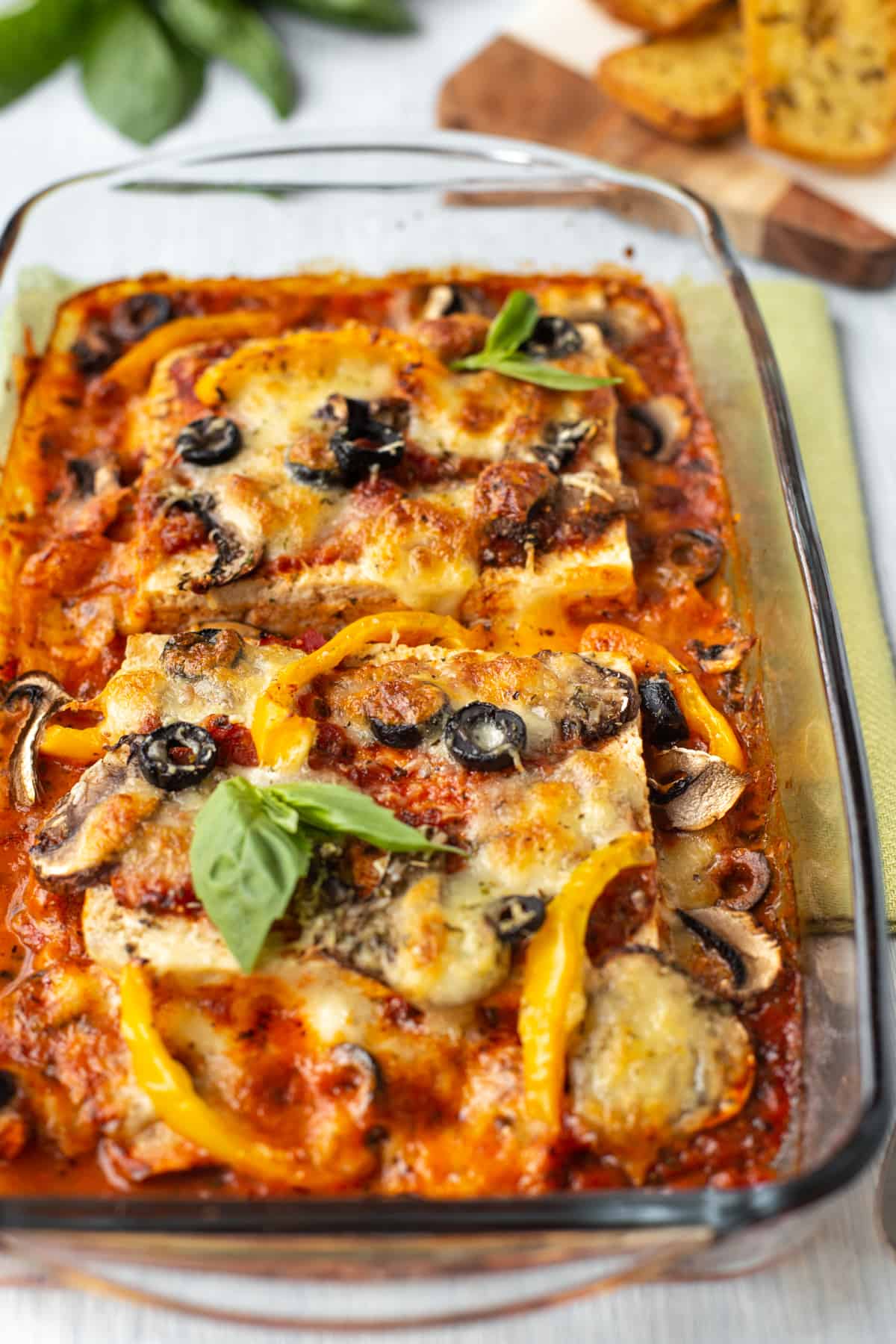Pizza baked tofu in a baking dish, with peppers and olives.