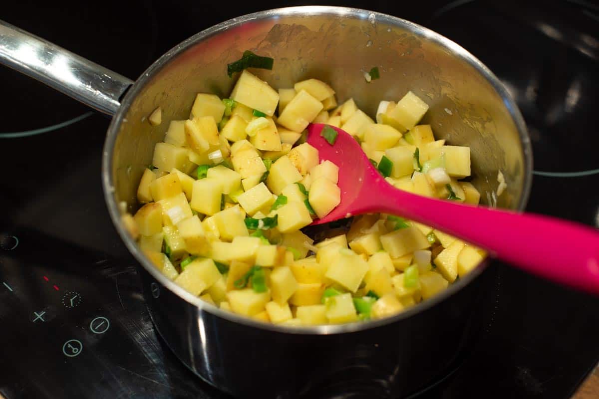 Diced potatoes and spring onions in a saucepan.