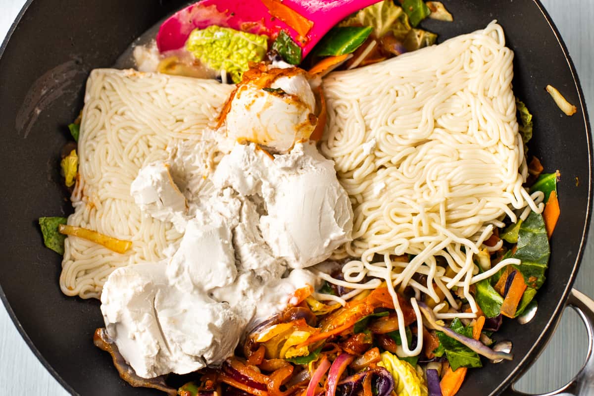 Vegetables, fresh egg noodles and coconut milk in a wok.