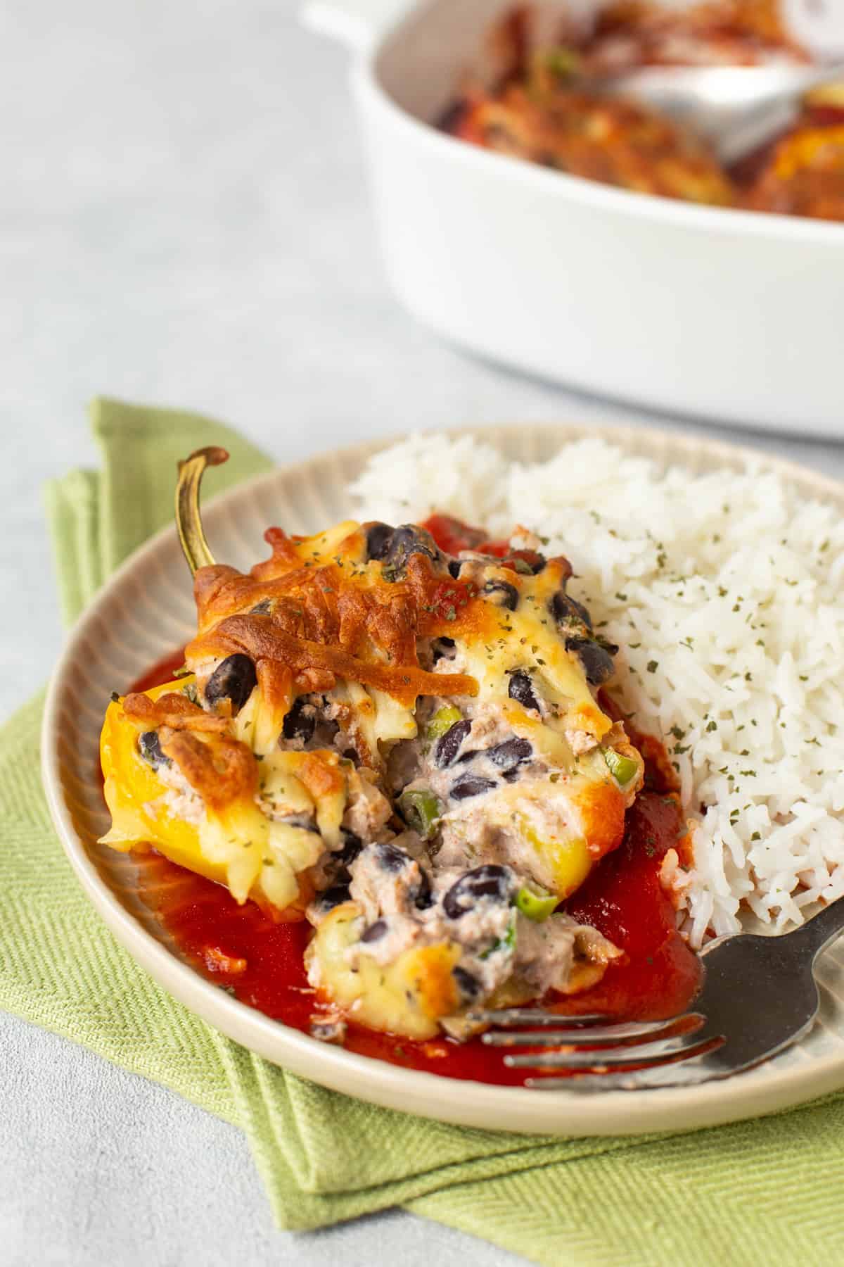 A stuffed pepper filled with creamy ricotta and black beans, on tomato sauce with rice.