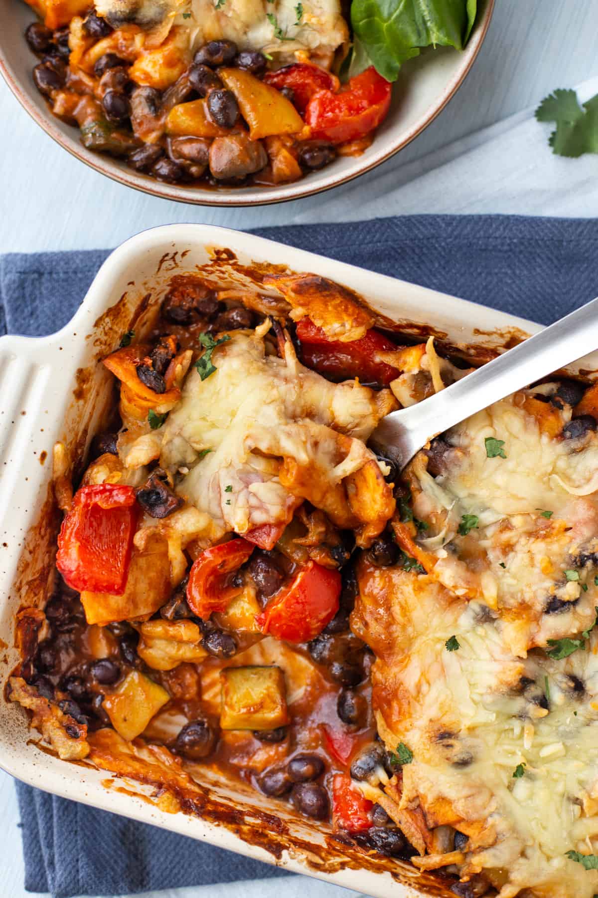 Enchilada casserole in a baking dish with a large scoop removed.
