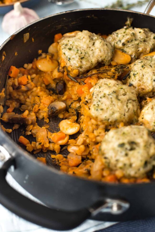 Vegan cassoulet in a pan topped with herbed dumplings.