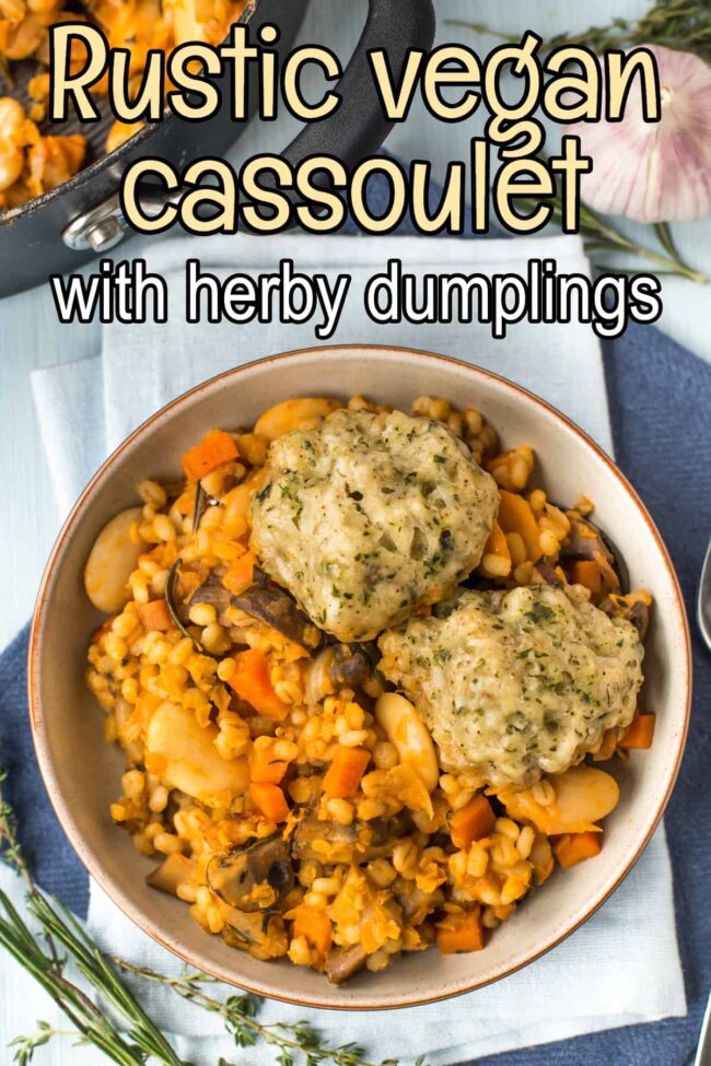 A portion of vegan cassoulet in a bowl topped with herby suet dumplings.