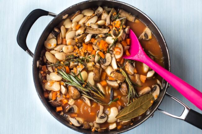 Vegan cassoulet with butter beans and fresh herbs cooking in a pan.