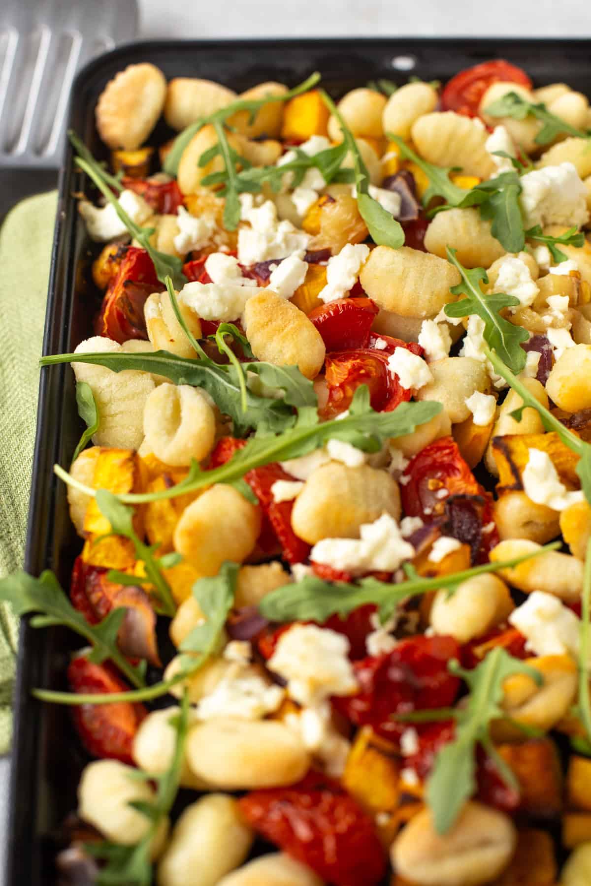 Gnocchi and pumpkin on a sheet pan with arugula and feta.