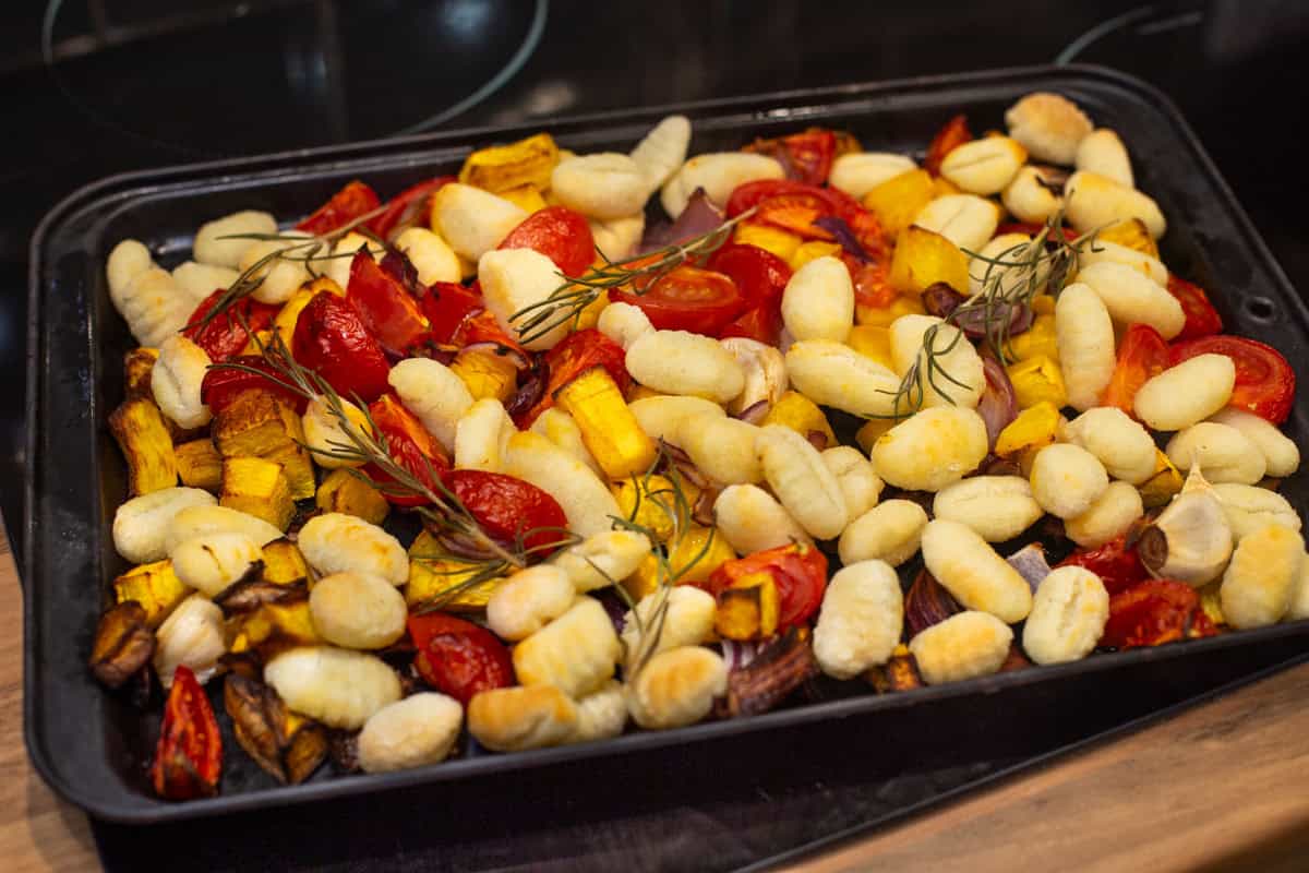 Roasted gnocchi with tomatoes and pumpkin topped with rosemary.