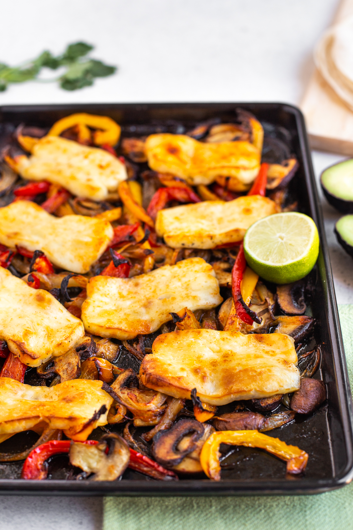 Roasted vegetables and halloumi on a baking tray.
