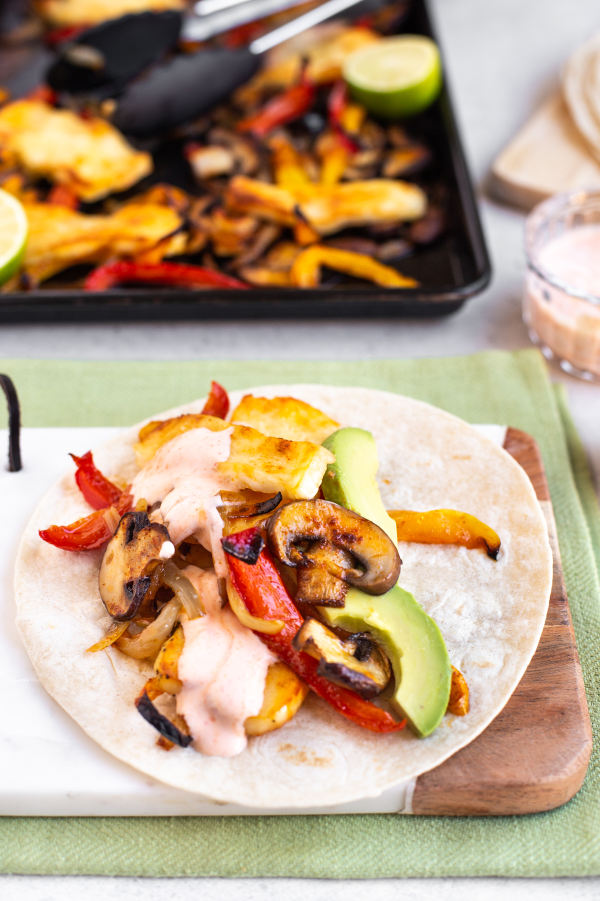 A vegetarian halloumi fajita topped with avocado.