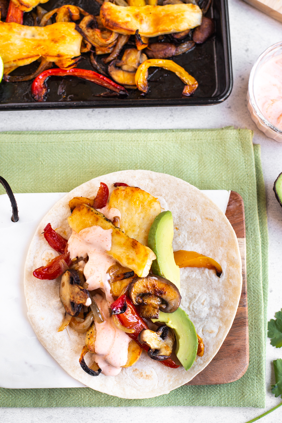 A halloumi fajita topped with sliced avocado and chipotle sour cream.