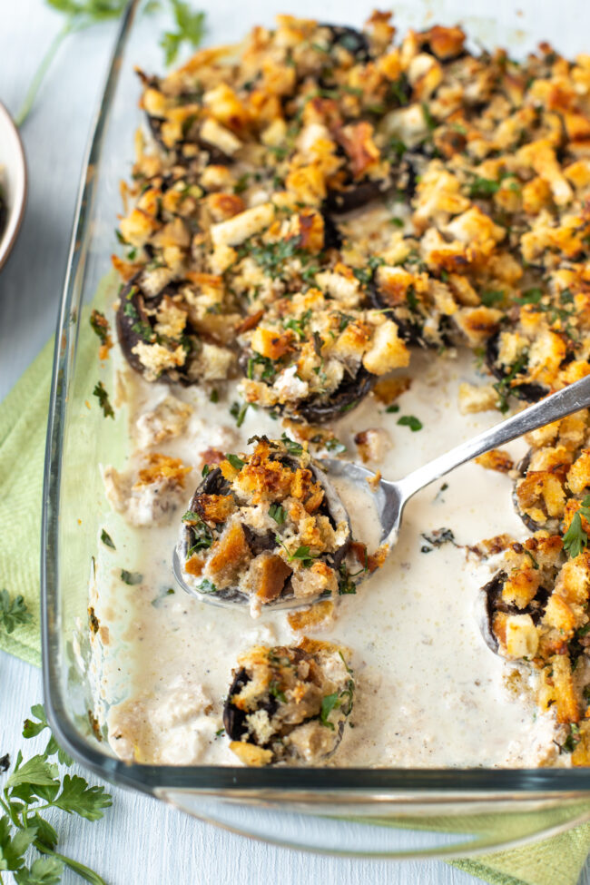 Crispy stuffed mushrooms in a baking dish with a cream sauce.