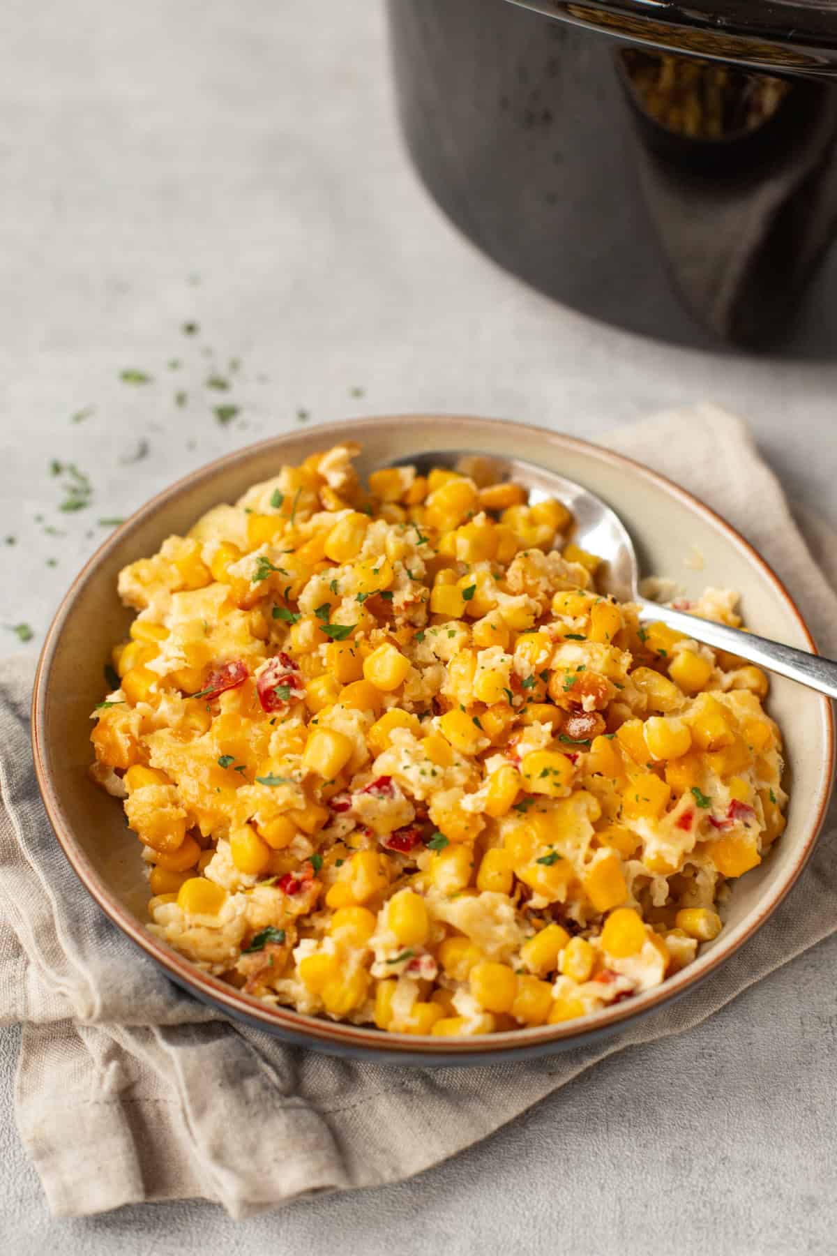 A bowl of slow cooker corn casserole with a spoon.
