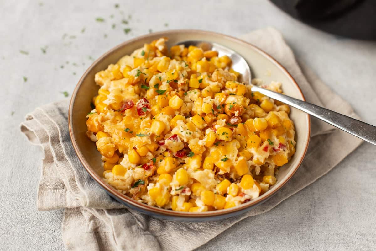A bowl of slow cooker corn casserole with a spoon.