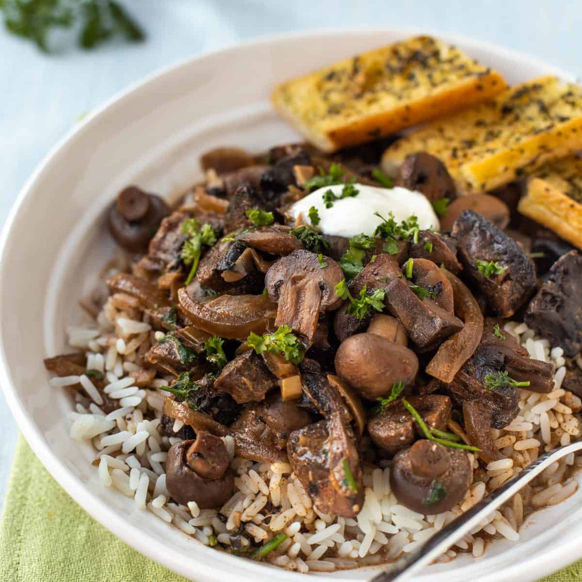 Mushroom stroganoff in a bowl with rice and parsley.
