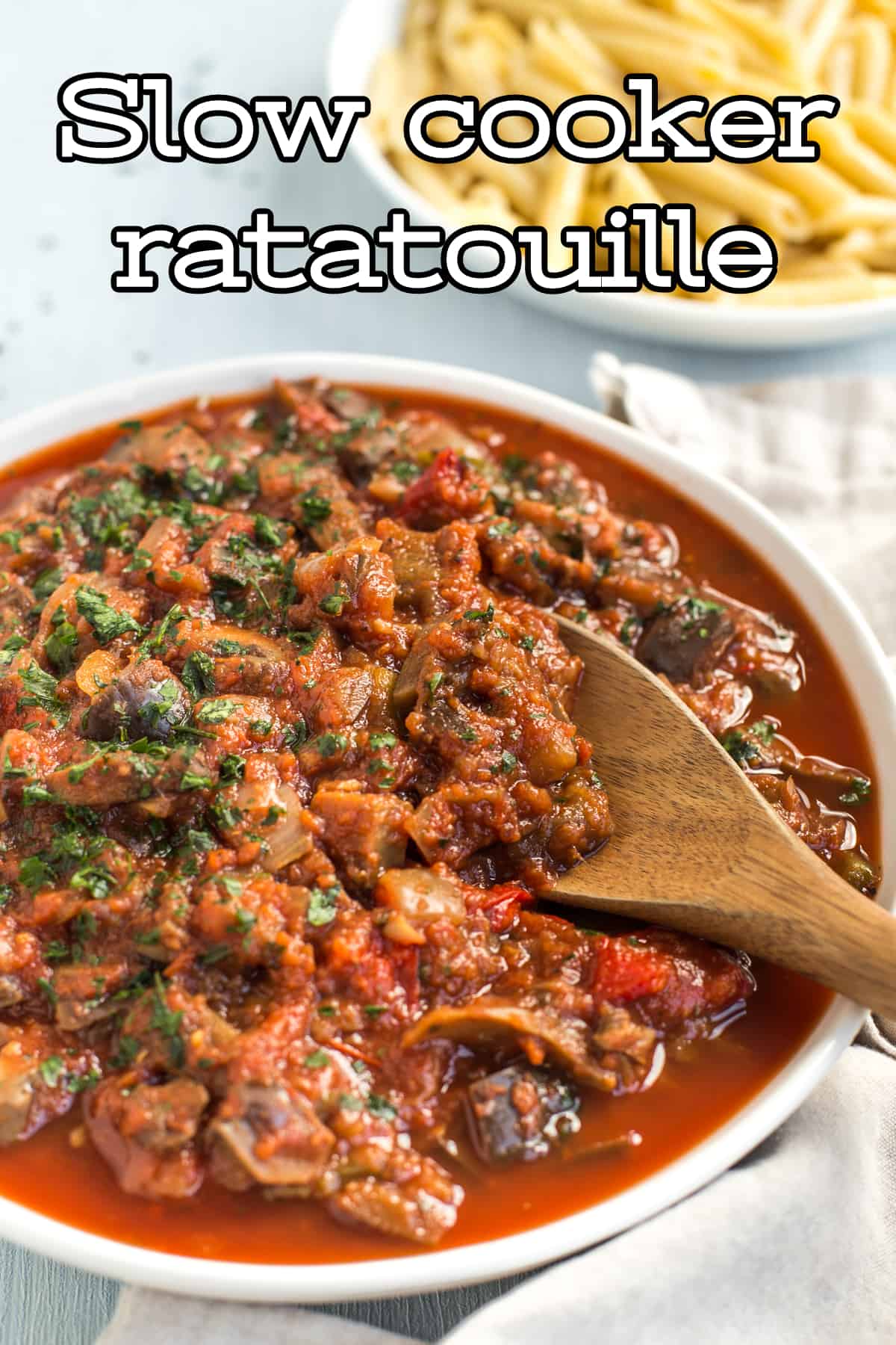 Slow cooker ratatouille in a bowl being scooped with a wooden spoon.
