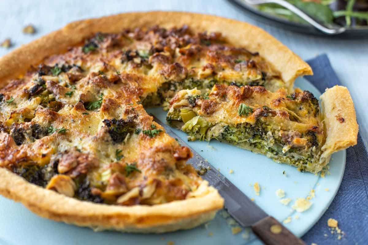 Smoked cheese and broccoli tart being cut into slices.