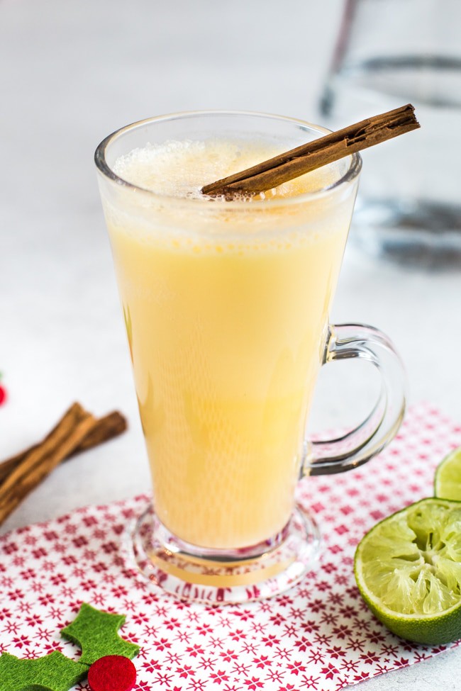 A snowball cocktail in a glass mug with a cinnamon stick.