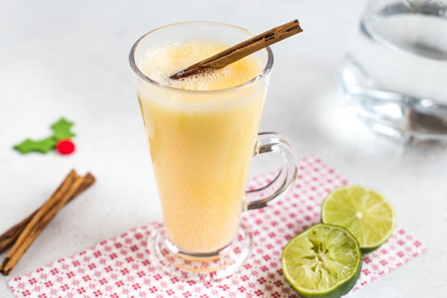 A snowball cocktail in a glass mug with a cinnamon stick.