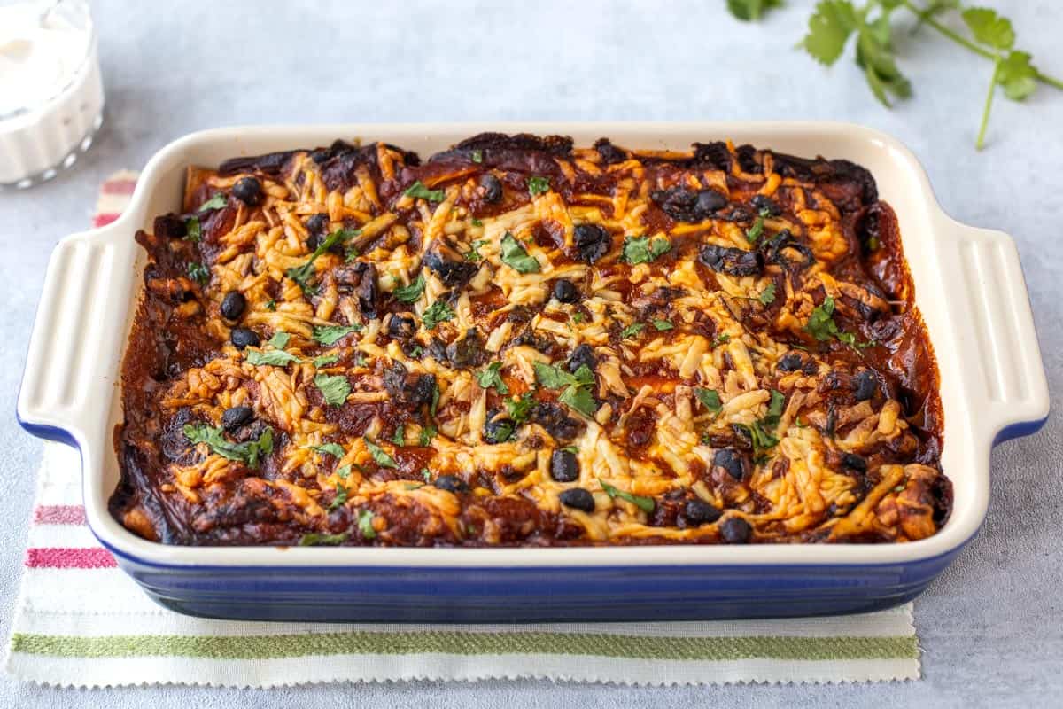 Cheesy black bean enchiladas in a baking dish.