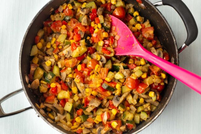 Colourful summer vegetables cooking in a pan.
