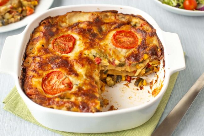 Summer vegetable lasagne A crispy vegetable lasagne in a baking dish, with a slice removed so you can see the layers.