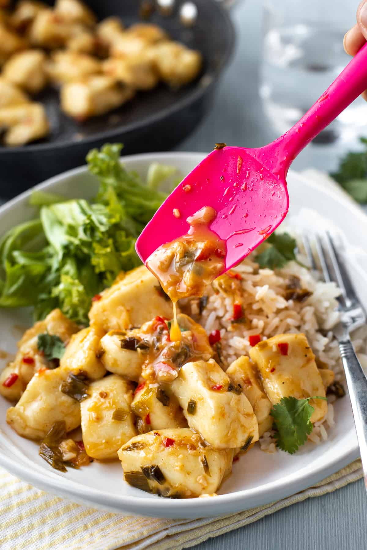 Sticky sauce being drizzled over chunks of halloumi cheese in a bowl.