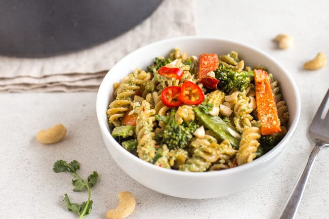 Thai pesto pasta with lots of vegetables in a white bowl