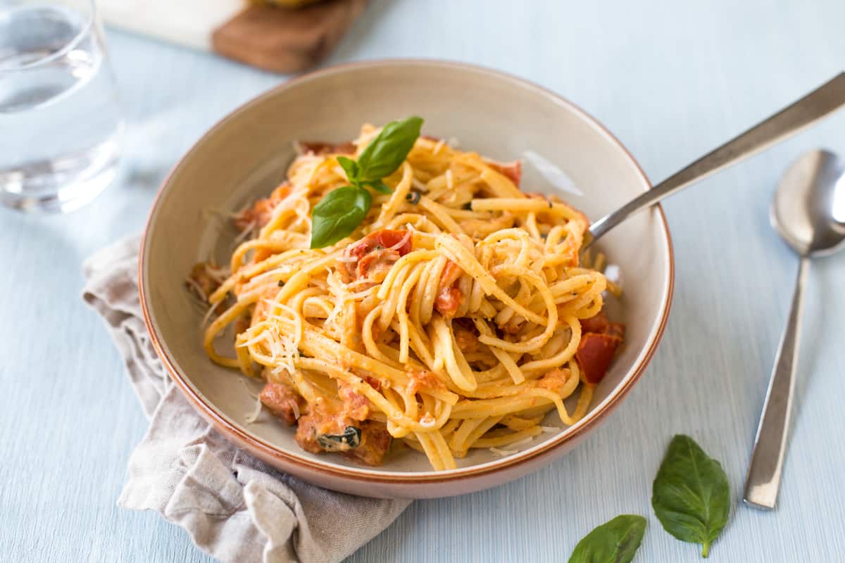 Tomato and mascarpone pasta in a bowl with fresh basil.