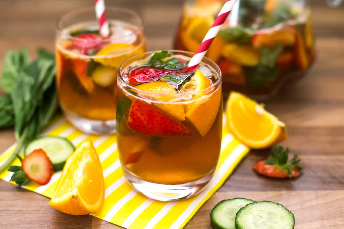 A glass of Pimm's with fresh fruit and a straw.