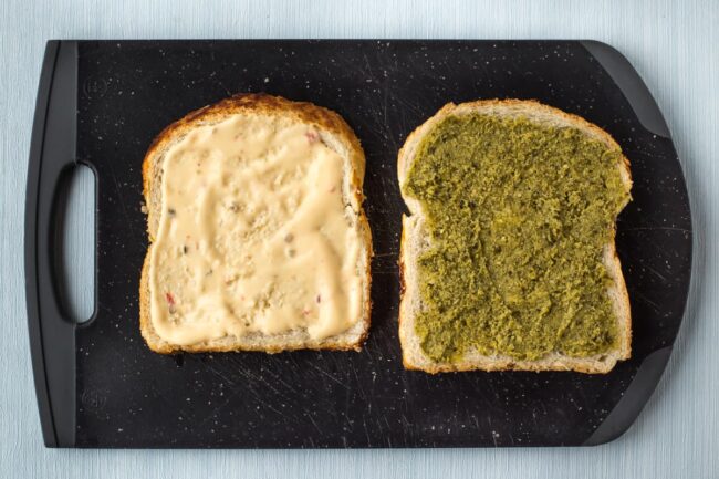 Slices of bread spread with pesto and mayonnaise.